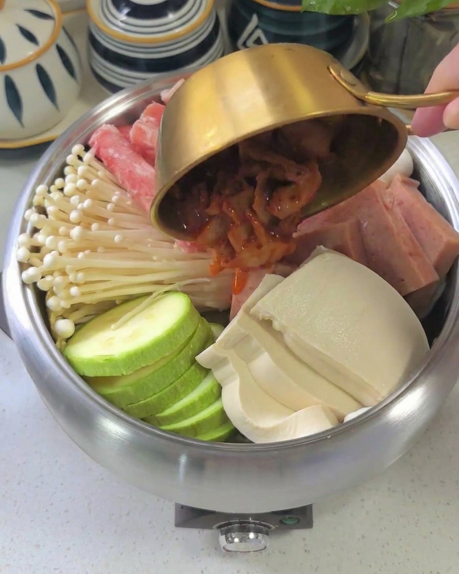 Die dickflüssige, dunkelrote Sauce wird über die geschichteten Zutaten im Topf gegossen.