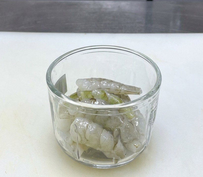 Rohe, durchscheinende Garnelen in einem Glasmixer auf einem weißen Schneidebrett.