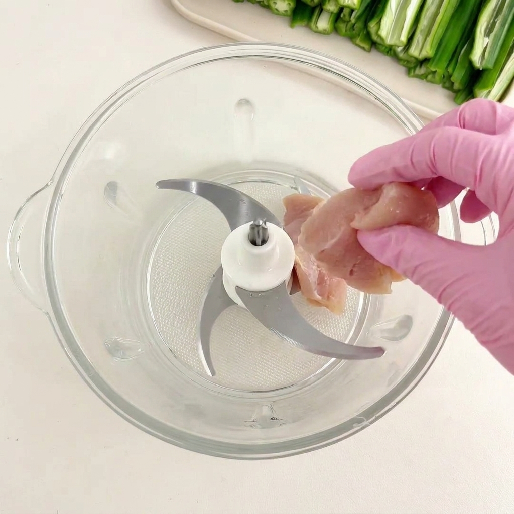 Hähnchenstücke werden in den Glasbehälter eines Mixers gegeben.