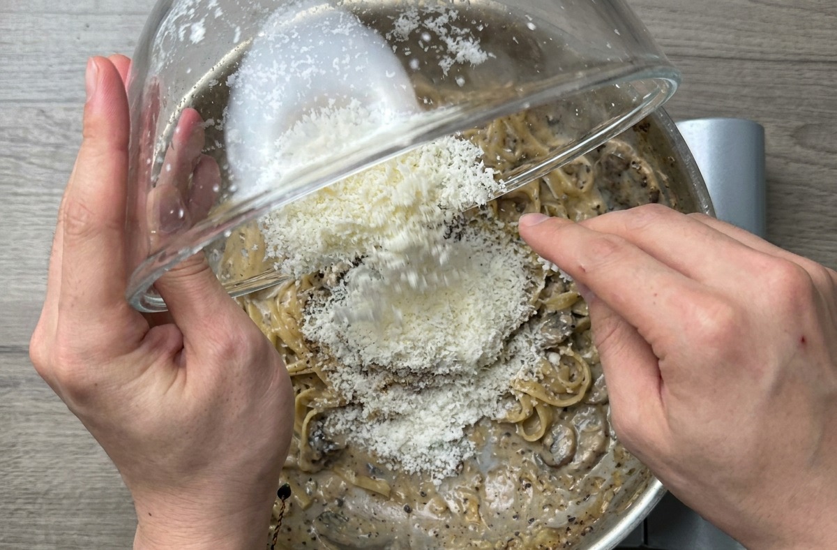 Nahaufnahme der fertigen Spaghetti, die in der Pfanne kräftig geschwenkt werden, um eine glänzende Sauce zu erzeugen.