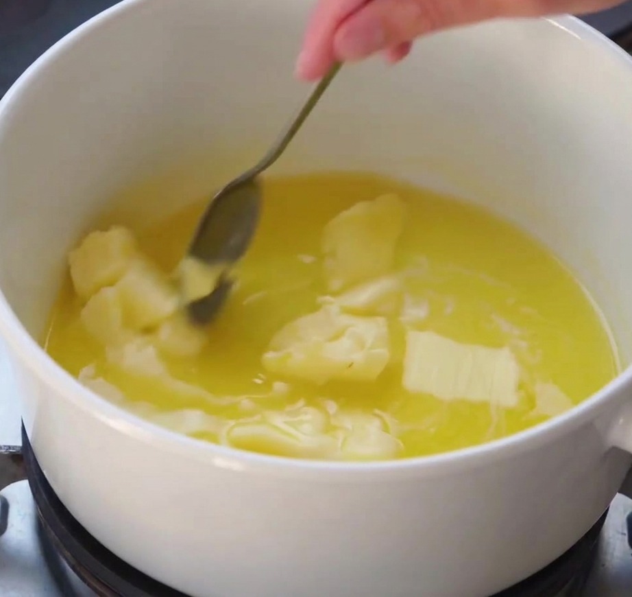 Ein Schneebesen rührt eine glatte weiße Sauce an, die in einem Topf auf dem Herd andickt