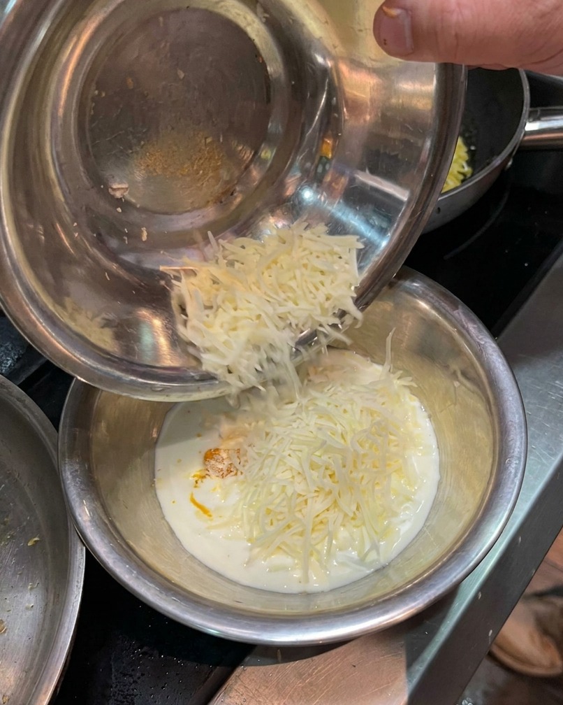 Geriebener Parmesan wird zur Eigelb-Sahne-Mischung in die Schüssel gegeben.