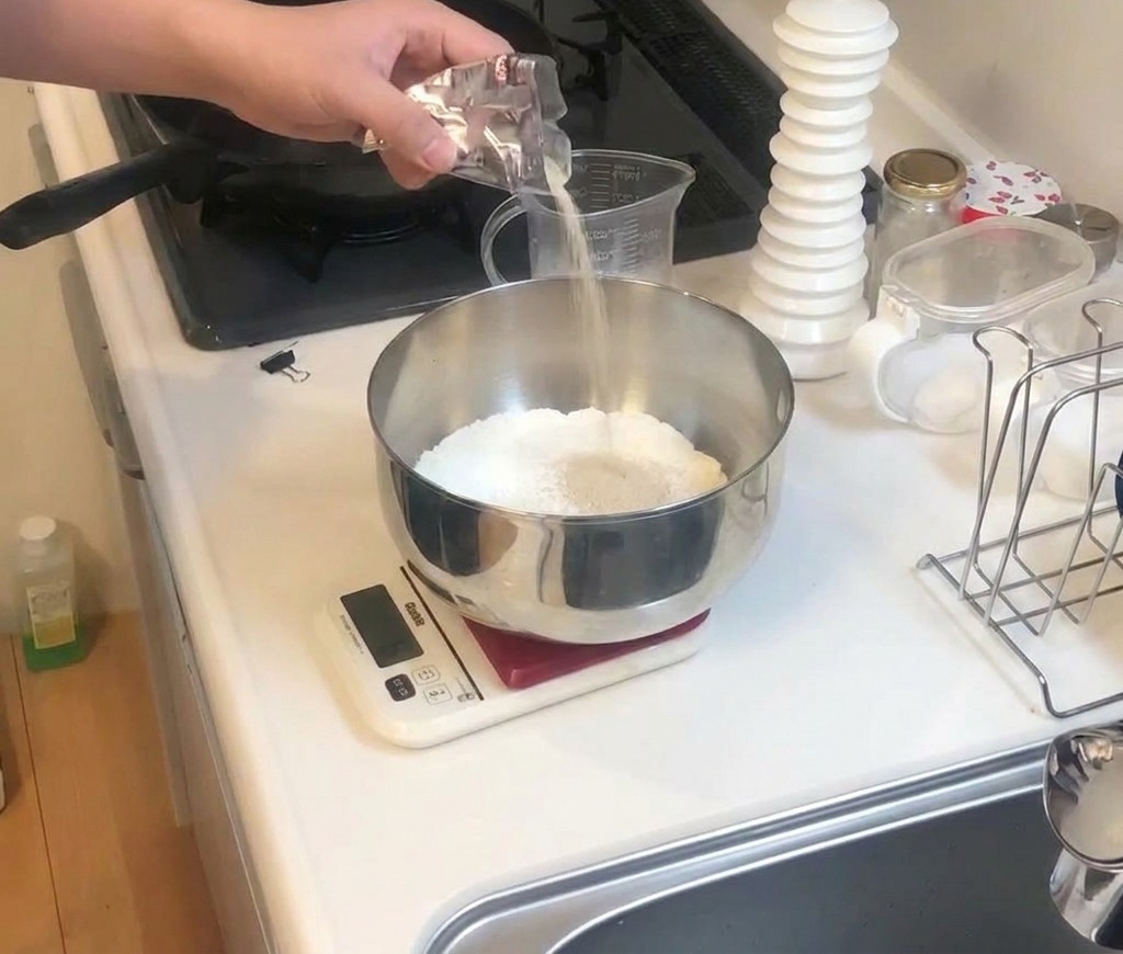 Eine Person gibt weißes Salz aus einem kleinen Tütchen in eine Schüssel mit Mehl.