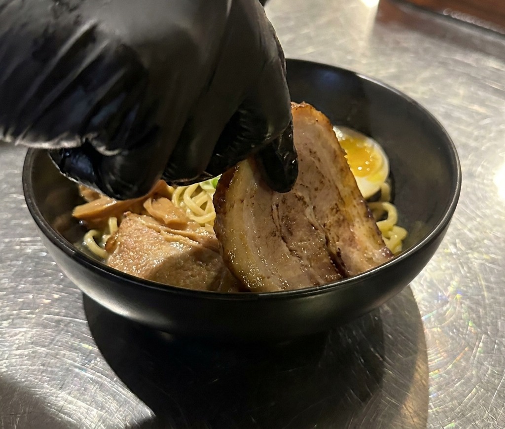 Zarte Scheiben von gebratenem Chashu-Schweinefleisch werden in die Schüssel gelegt.