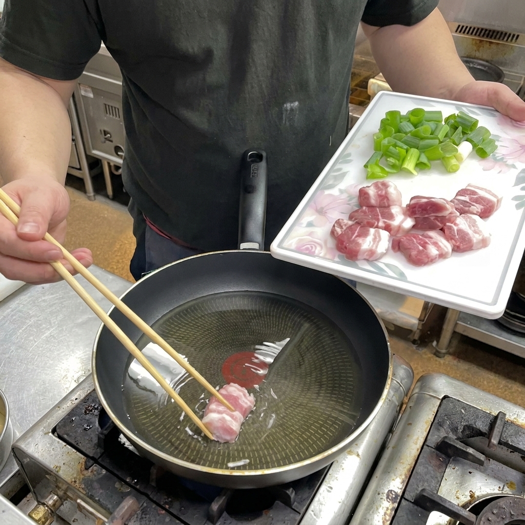 Mit Stäbchen werden dicke Scheiben rohen Schweinebauchs in eine Pfanne mit Reisöl gelegt.