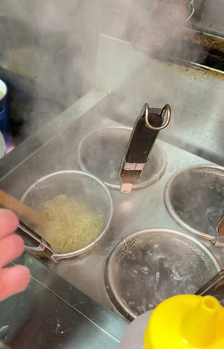 Nudeln garen in einem Sieb in einem Topf mit kochendem Wasser.