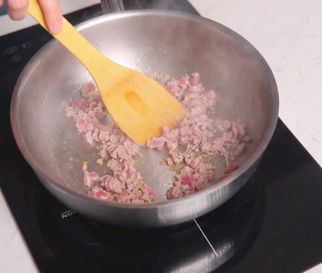 Hackfleisch wird in einer Pfanne mit einem gelben Pfannenwender braun angebraten.