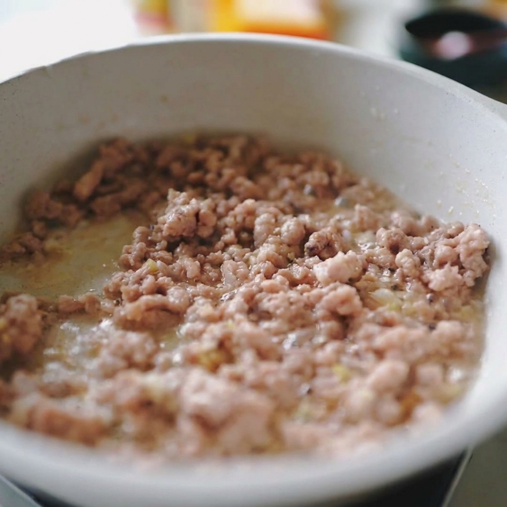 Hackfleisch und Zwiebelstreifen werden zusammen in der Pfanne angebraten.