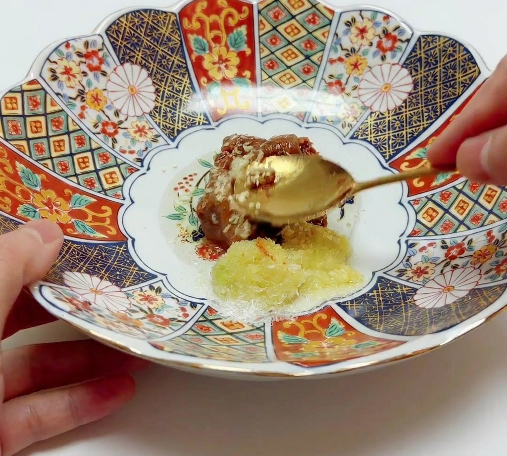 Ein goldener Löffel vermischt Misopaste mit Aromen und Öl in einer großen Keramikschale.