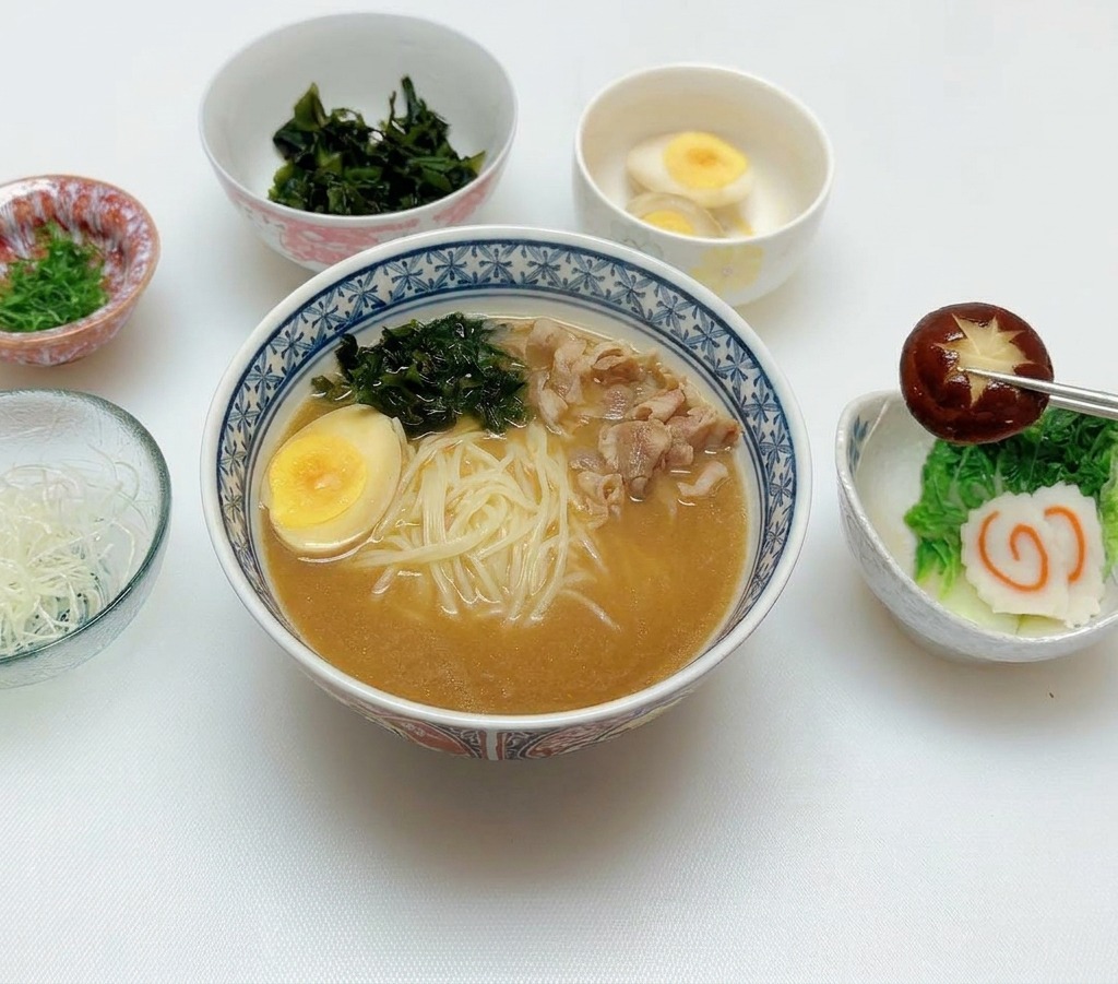 Essstäbchen legen einen eingeschnittenen Shiitake-Pilz auf die Ramen-Toppings.