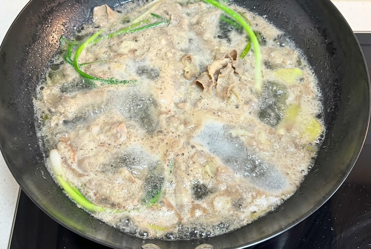 Dünn geschnittenes Rindfleisch und Frühlingszwiebeln in kochendem Wasser.