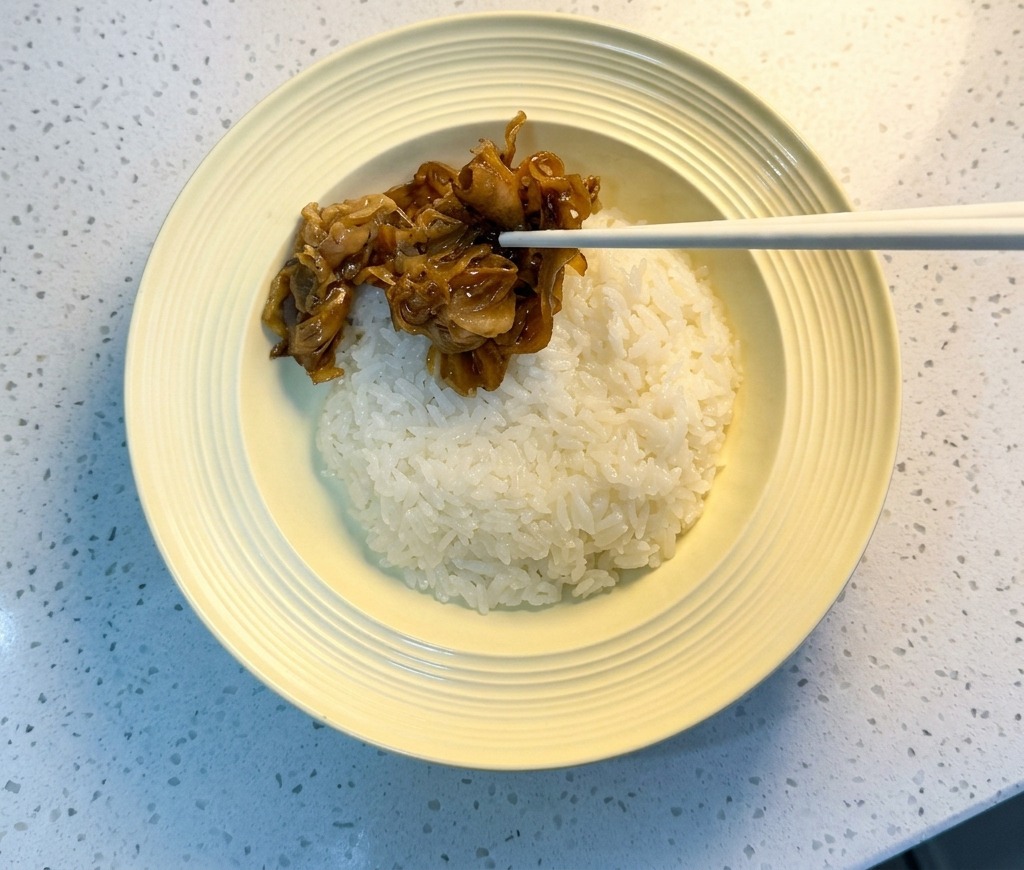 Essstäbchen legen glasiertes Fleisch auf eine Schüssel mit weißem Reis.