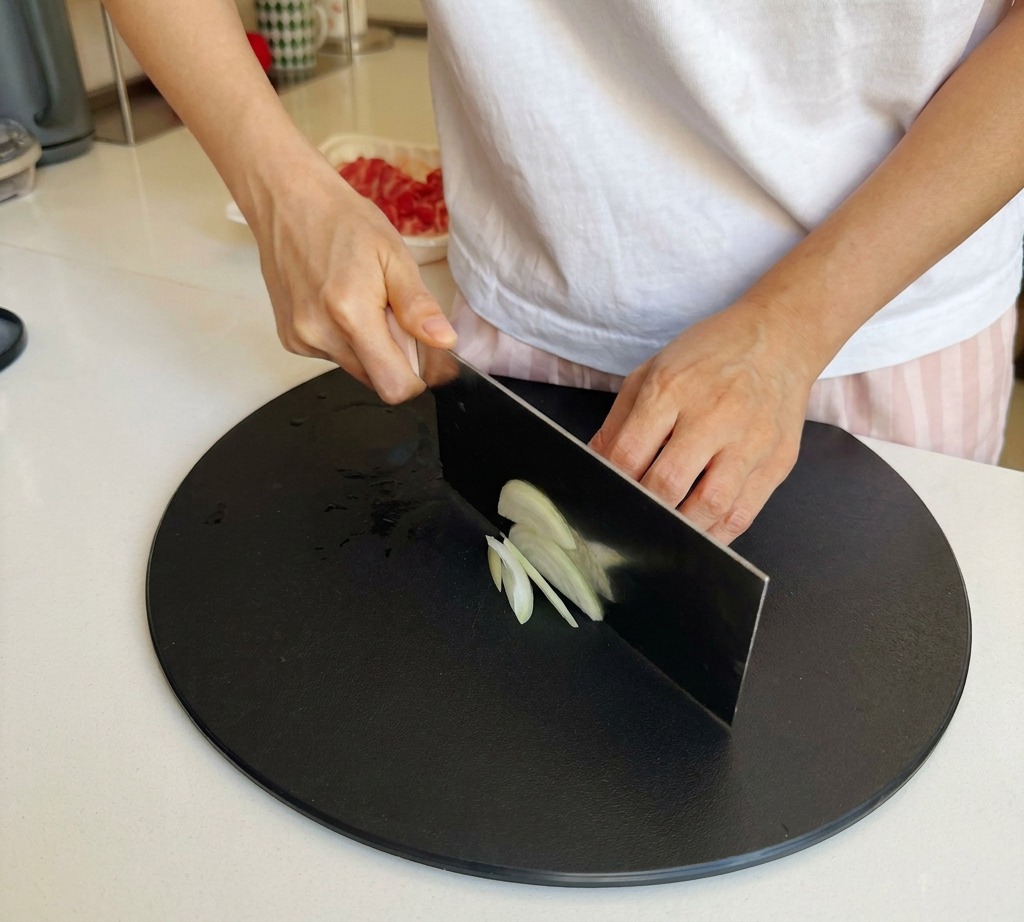 Eine weiße Zwiebel wird mit einem scharfen Messer in gleichmäßige, dünne Streifen geschnitten.