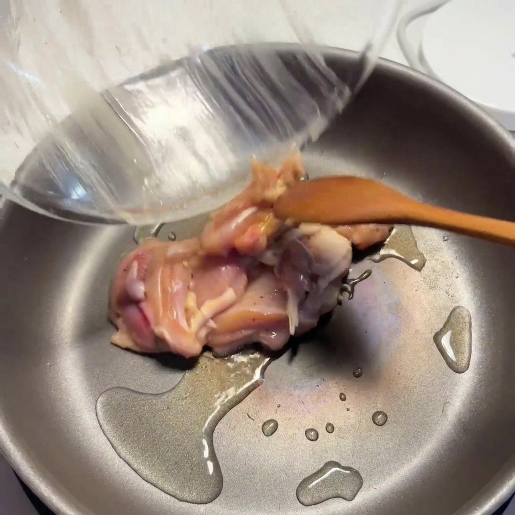 Gewürzte Hähnchenstücke werden in einer heißen Pfanne mit Öl angebraten, bis sie braun werden.