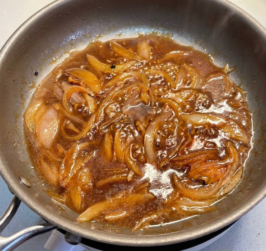 Lauchscheiben werden in die köchelnde Sauce mit den weichen Zwiebeln gegeben.