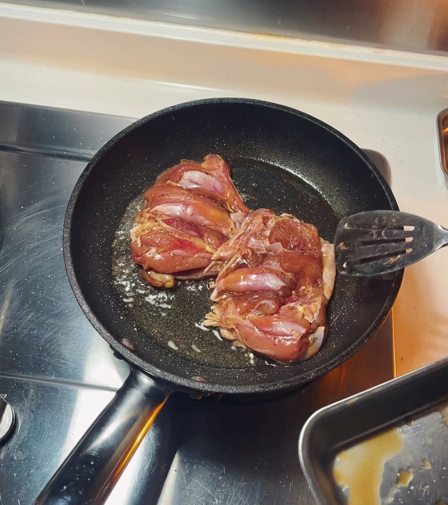 Hähnchenschenkel braten mit der Hautseite nach unten in einer schwarzen Pfanne, bis die Haut braun ist.