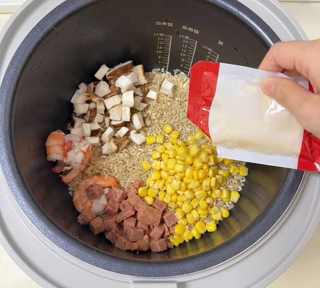 Maiskörner werden in einen Reiskocher mit Reis, Garnelen, Pilzen und Fleisch geschüttet.
