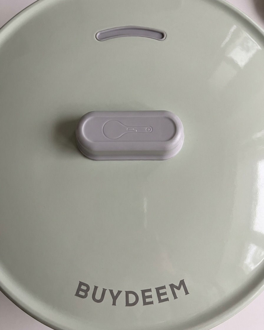 Der hellgrüne Deckel eines modernen Reiskochers wird geschlossen.