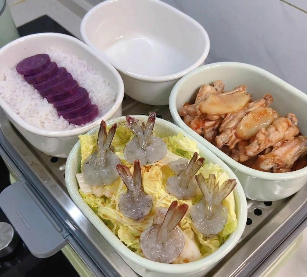 Eine ovale Schüssel mit Chinakohlblättern und rohen, geschälten Garnelen steht bereit für den Dampfgarer.