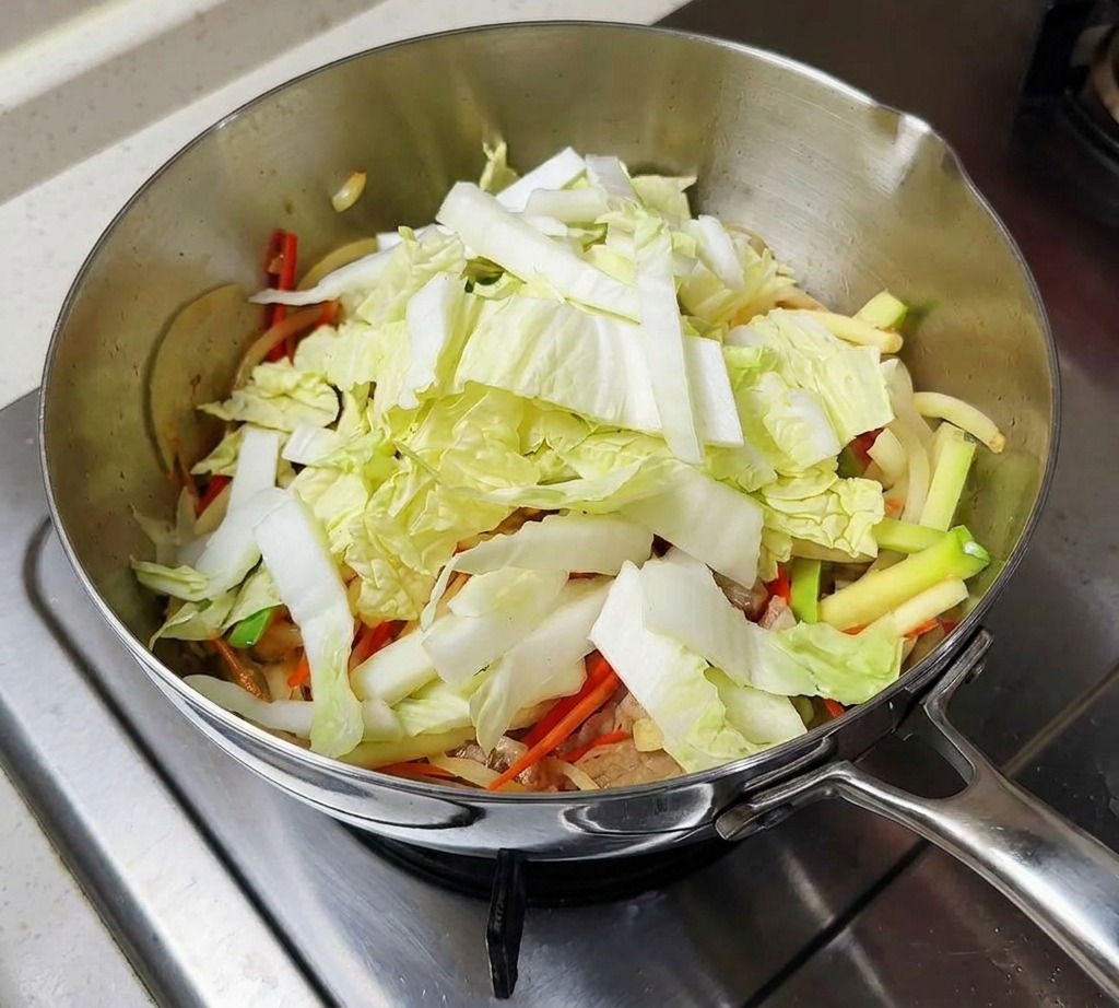 Gehackter Kohl und Shiitake-Pilze befinden sich im Kochtopf.