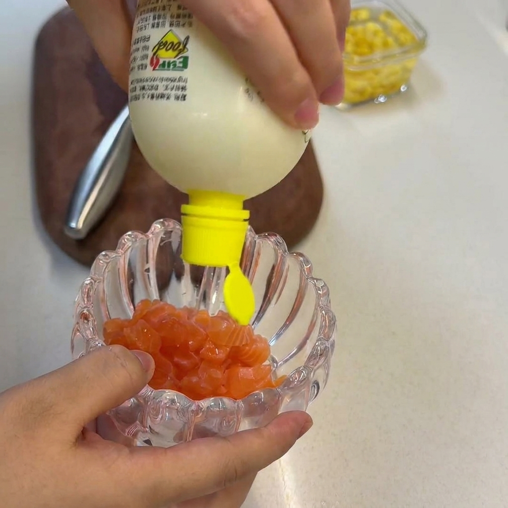 Frischer Zitronensaft wird aus einer gelben Flasche über rohe Lachswürfel in einer Glasschale gegossen.