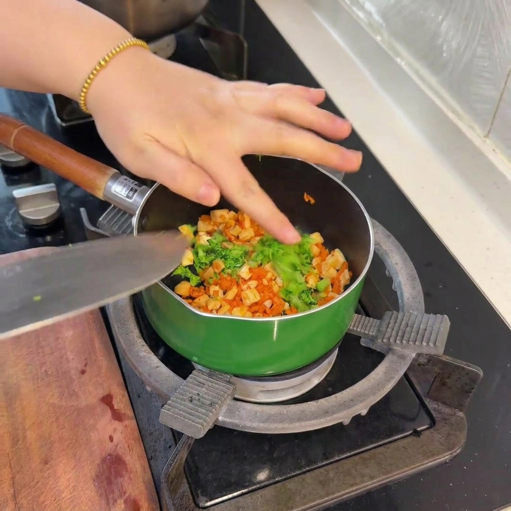 Kleine Stücke von hellgrün blanchiertem Brokkoli werden in die Pfanne zu Lachs und Karotten gegeben.