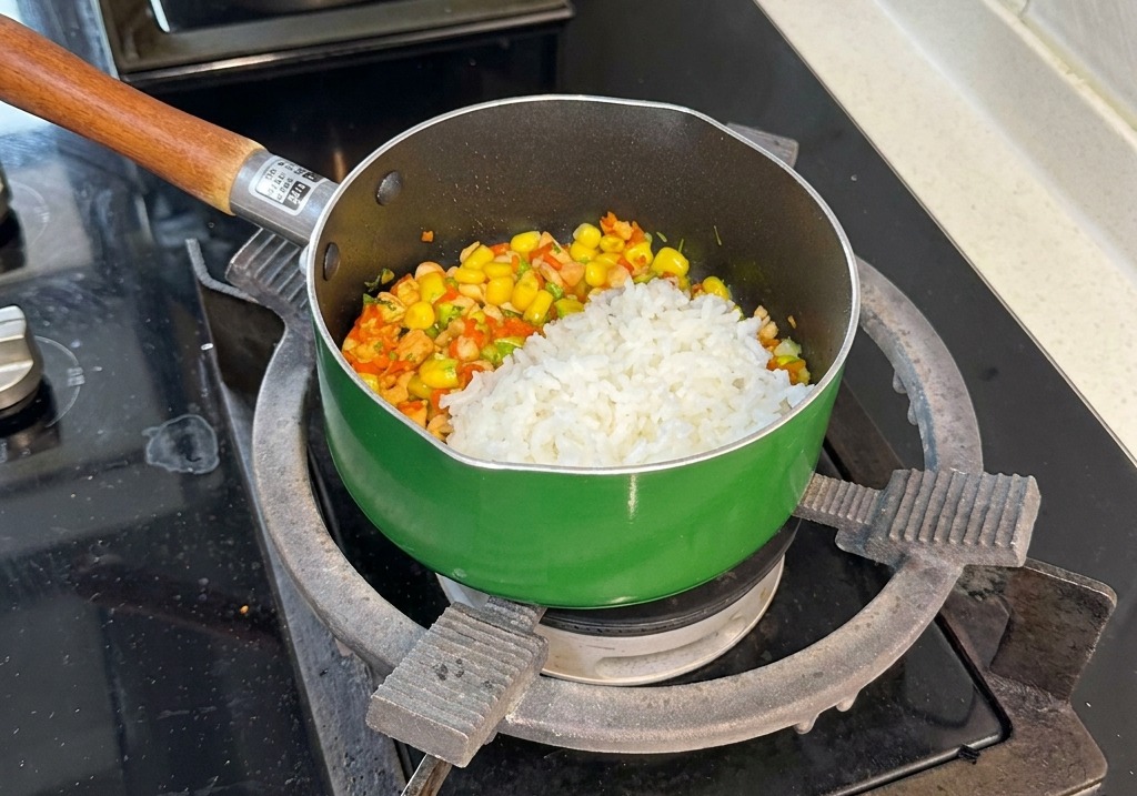 Eine Portion weißer gedämpfter Reis liegt auf der bunten Mischung aus Lachs, Mais, Karotten und Brokkoli.