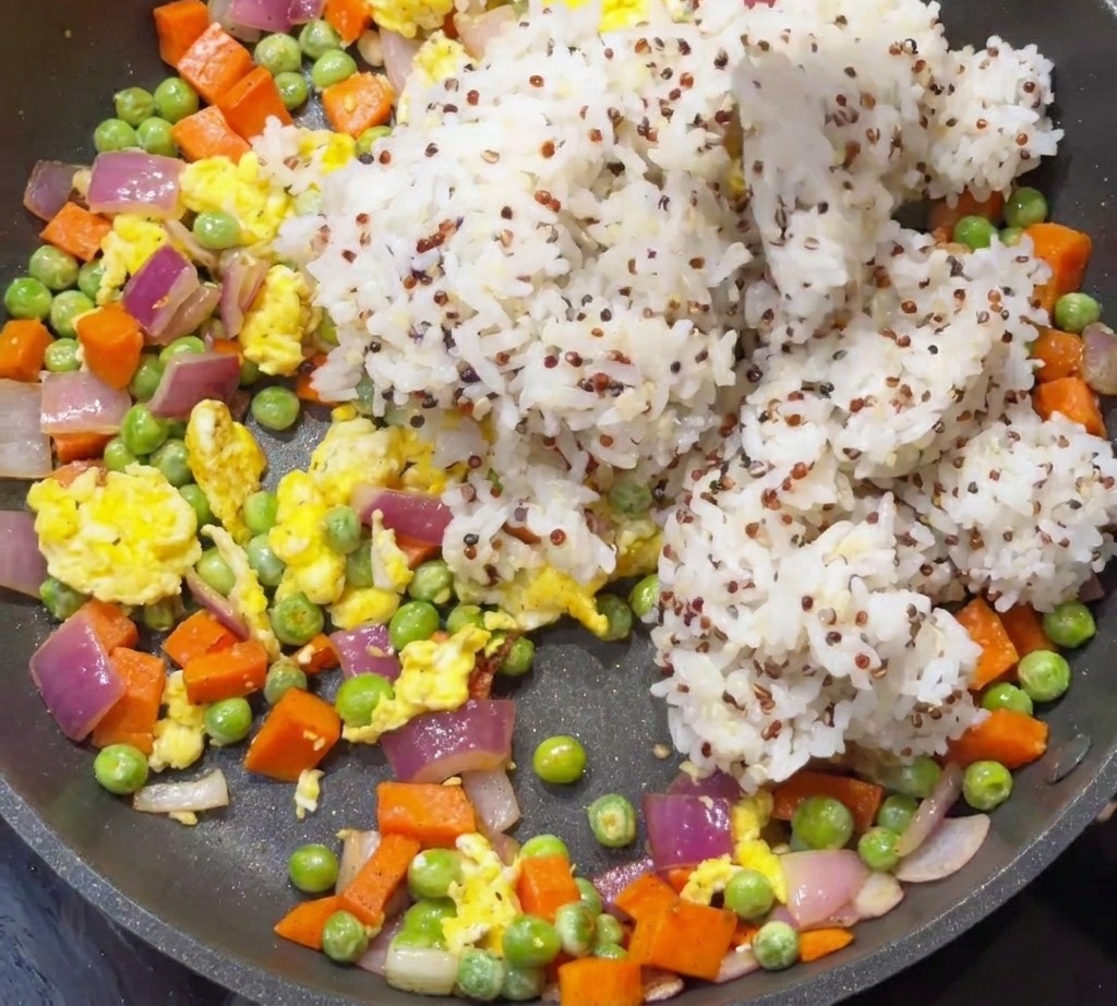 Gekochter weißer Reis und Quinoa werden in eine Pfanne mit gedünstetem Gemüse und Eiern gegeben.