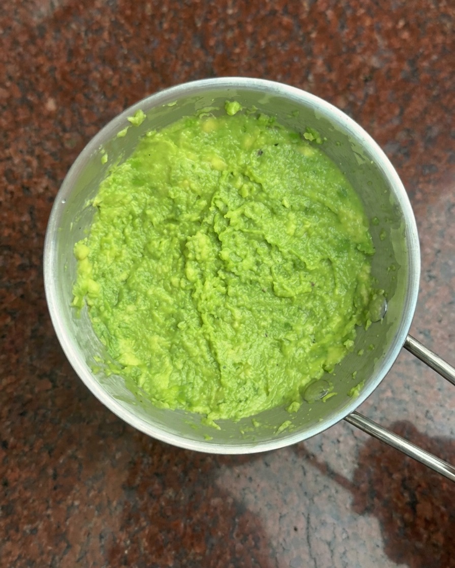 Draufsicht auf eine kleine Metallschüssel mit einer leuchtend grünen Avocado-Paste.