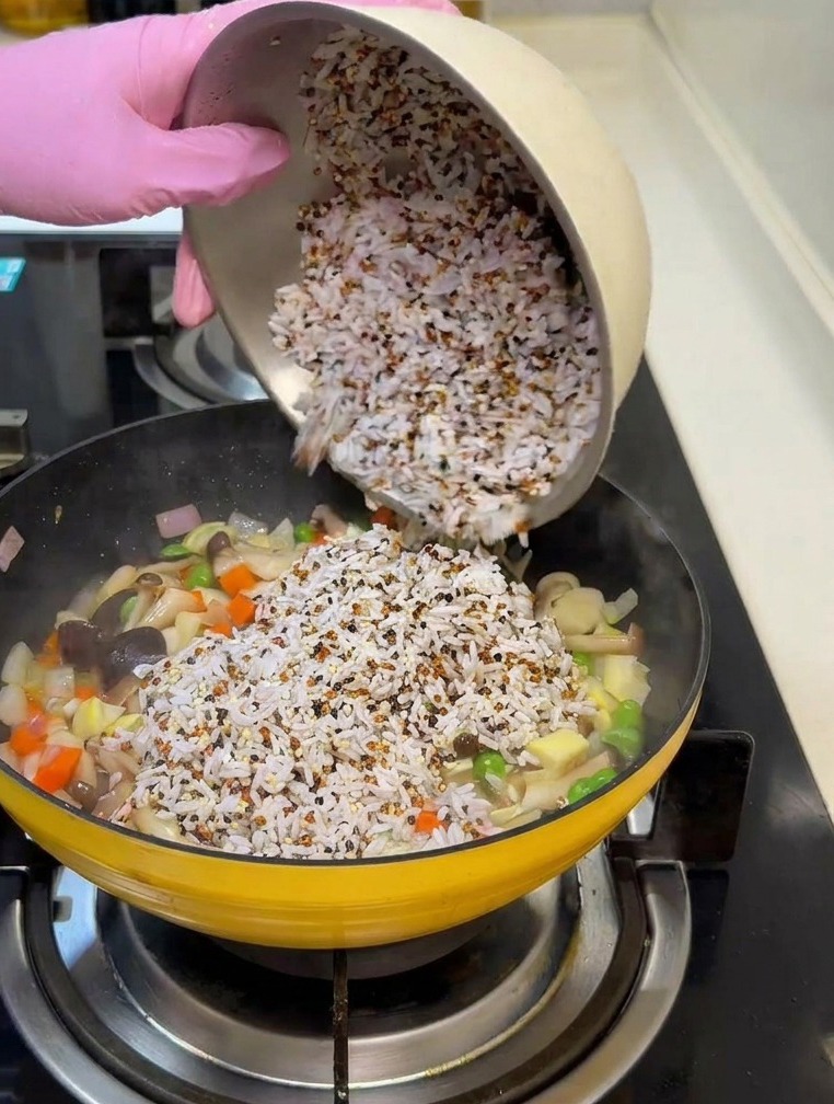 Die Mischung aus Reis und Quinoa wird über das gebratene Gemüse gegossen.