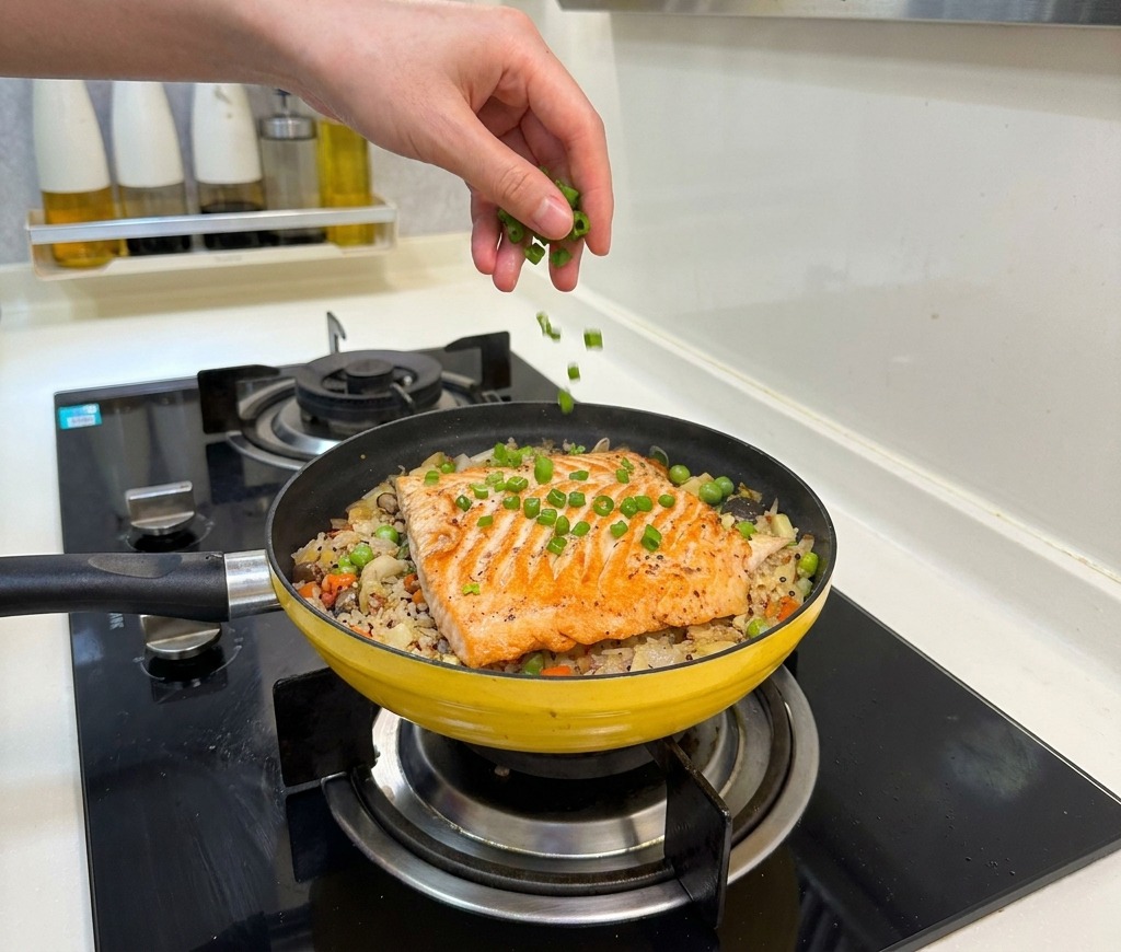 Frisch gehackte Frühlingszwiebeln werden über das fertige Lachs-Reis-Gericht gestreut.