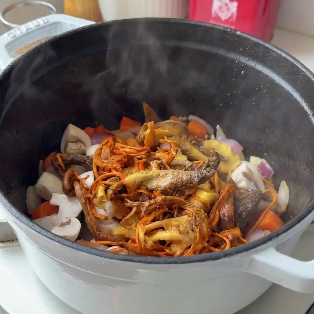 Verschiedene frische und getrocknete Pilze werden in einen Topf mit gedünstetem Gemüse gegeben.