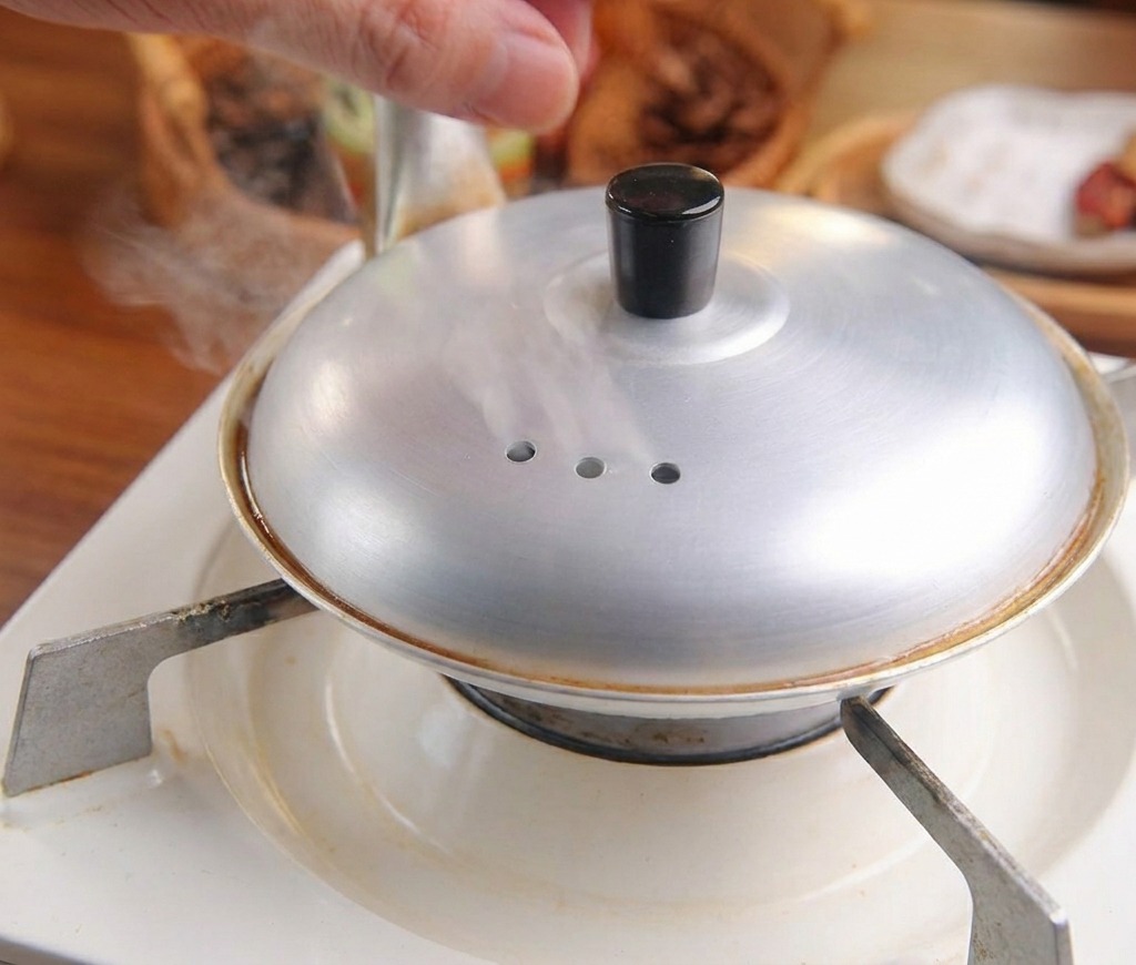 Ein Metalldeckel wird auf die Pfanne gesetzt, um das Ei im Dampf garen zu lassen.