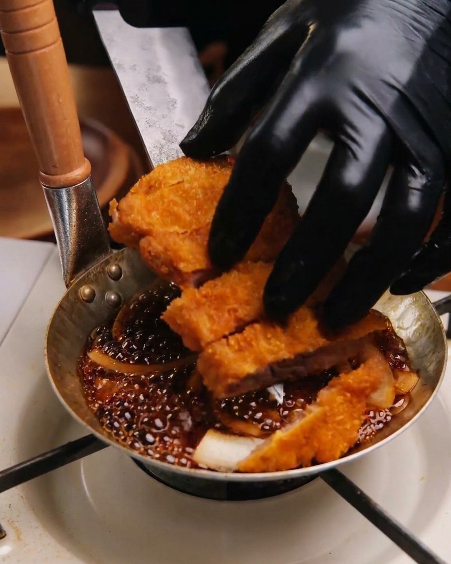 Geschnittenes Schnitzel wird auf das Bett aus Zwiebeln und Sauce in die Pfanne gelegt.