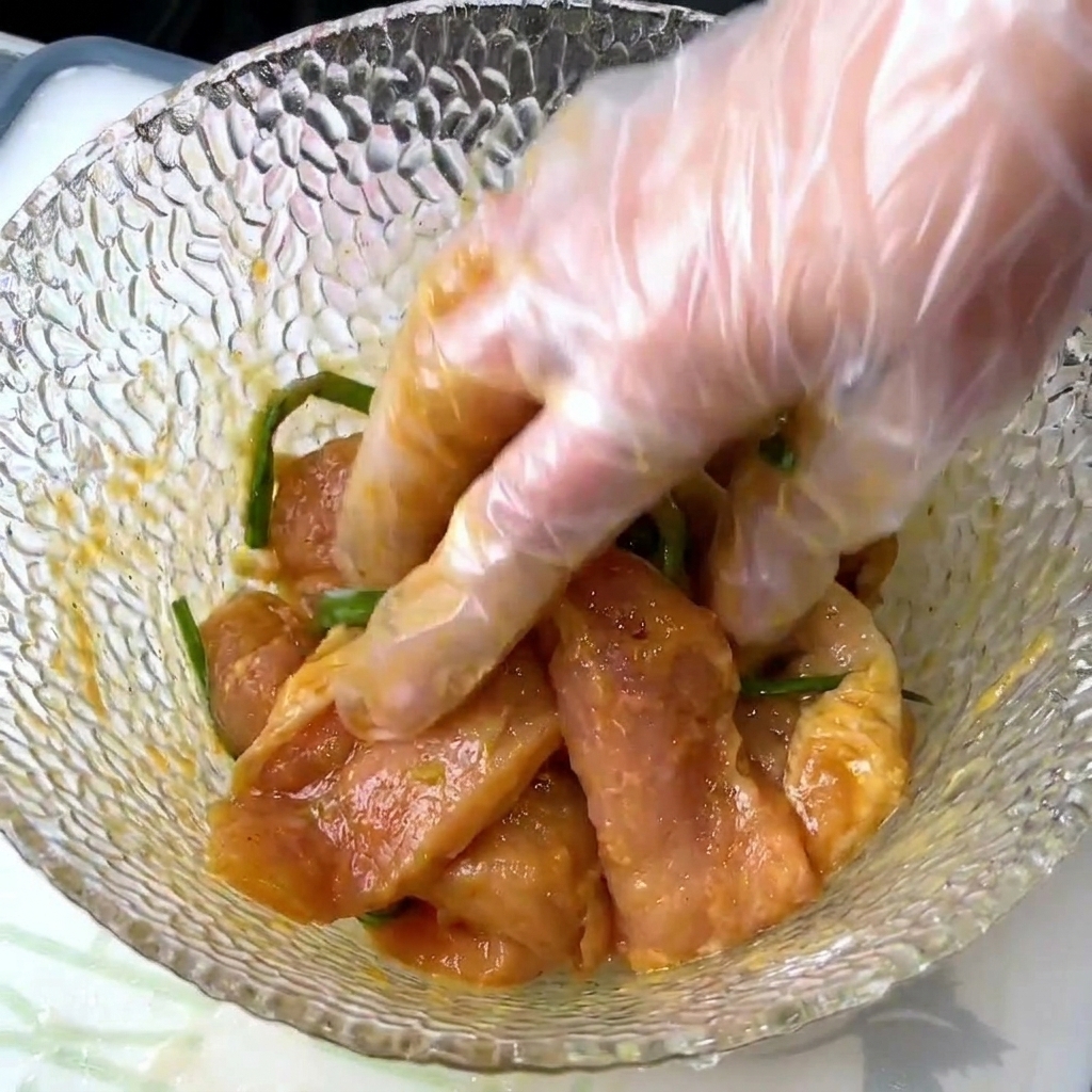 Eine Hand mischt rohes Schweinefleisch mit Gewürzen und Frühlingszwiebeln gründlich in einer Schüssel durch.