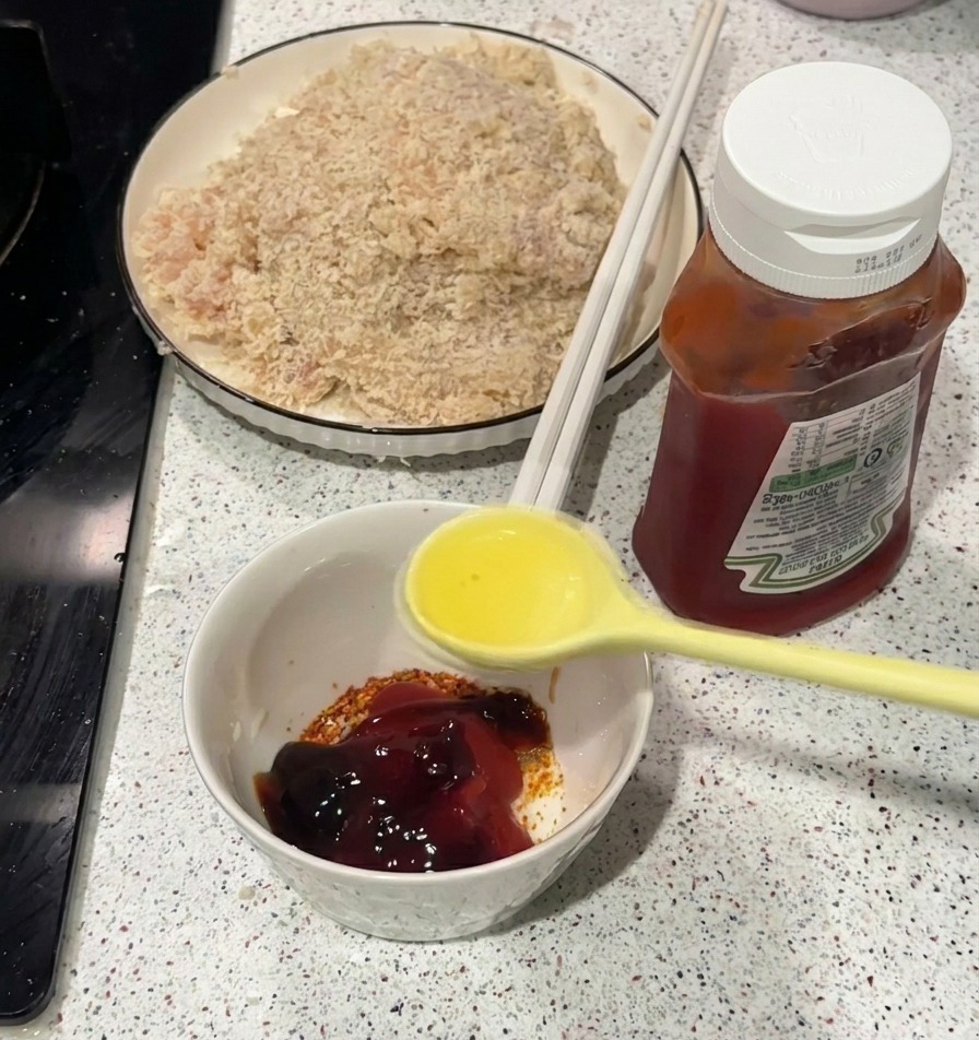 Ein gelber Löffel gießt heißes Öl in eine kleine weiße Schüssel mit Ketchup und Gewürzen.