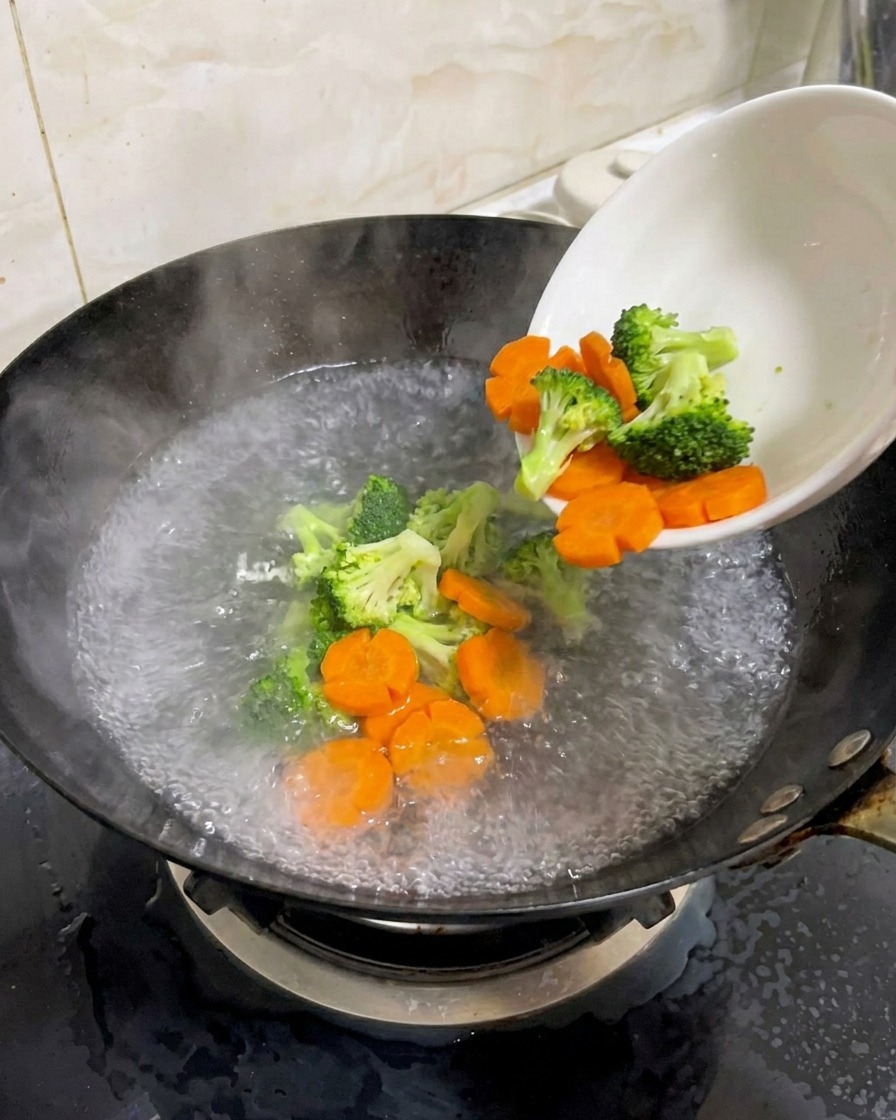 Brokkoli und Karottenblüten werden in einen Wok mit kochendem Wasser gegeben.