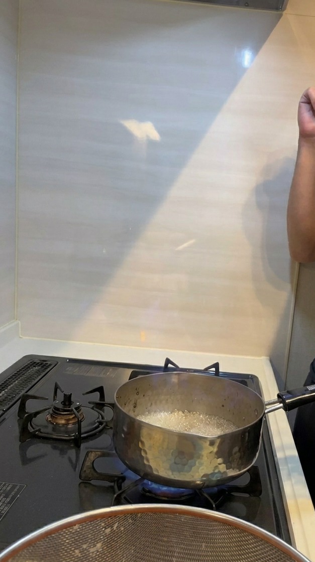 Eine dramatische blau-orange Flamme schlägt aus einem kleinen Topf auf einem brennenden Gasherd während des Flambierens.