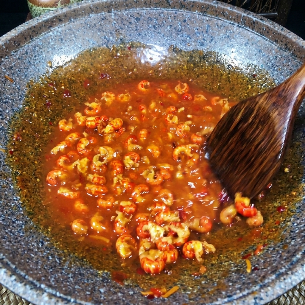 Ein Holzspatel rührt Flusskrebsfleisch in einer dicken, blubbernden roten Sauce.