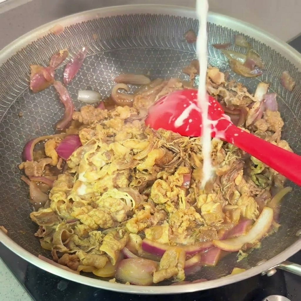 Ein dünner Strahl Stärkemischung wird in die Pfanne mit dem köchelnden Rindfleisch gegossen.
