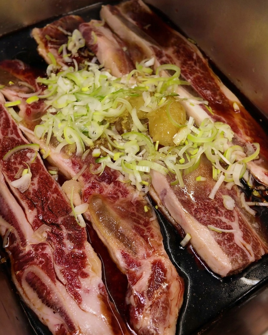 Geröstetes Sesamöl wird über das Fleisch und die Kräuter geträufelt.