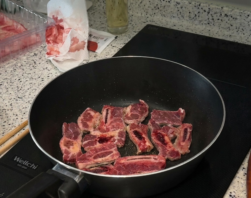 Das Fleisch in der Pfanne wird mit Salz und viel schwarzem Pfeffer bestreut.