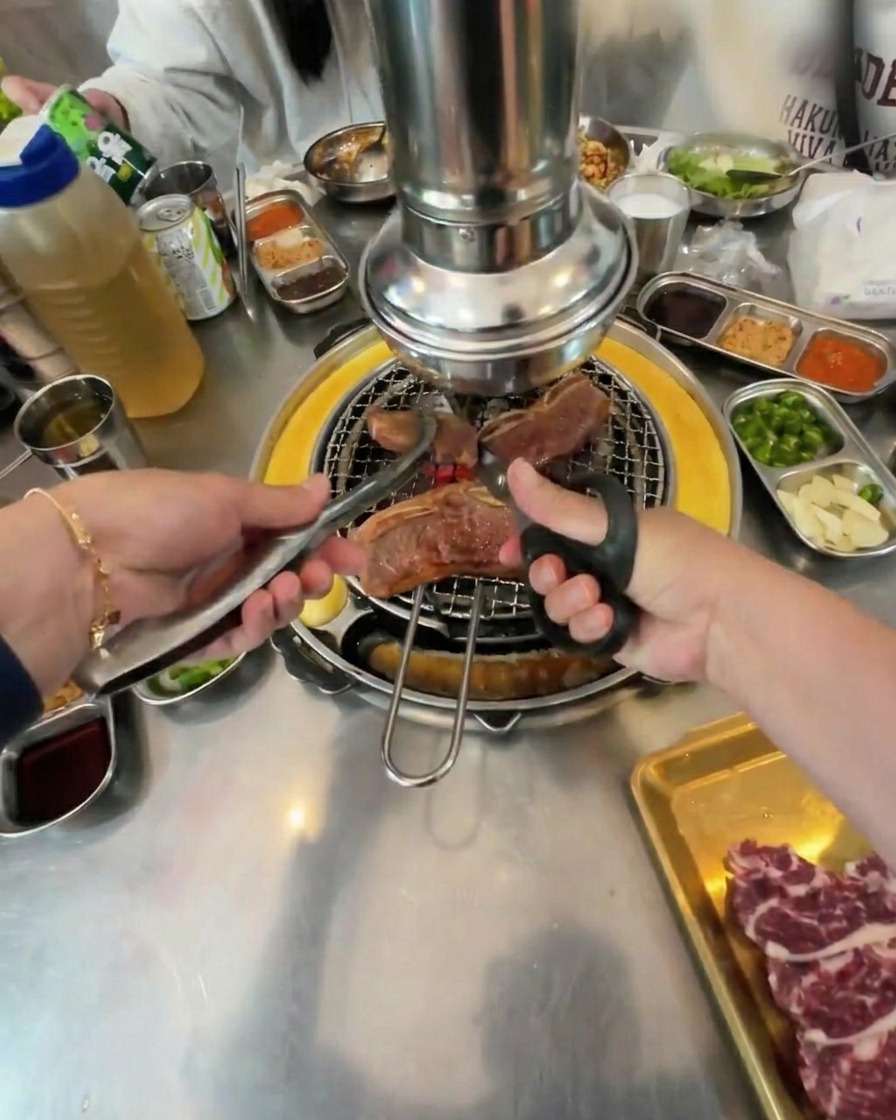 Mit Schere und Zange werden große Stücke des Rindfleischs direkt auf dem Grill zerschnitten.