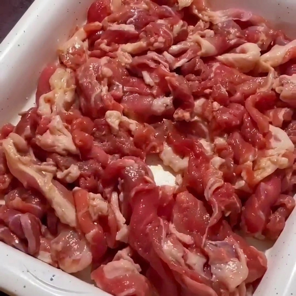 Nahaufnahme von Schweinefleisch in der Pfanne, das an den Rändern bereits braun und knusprig wird.