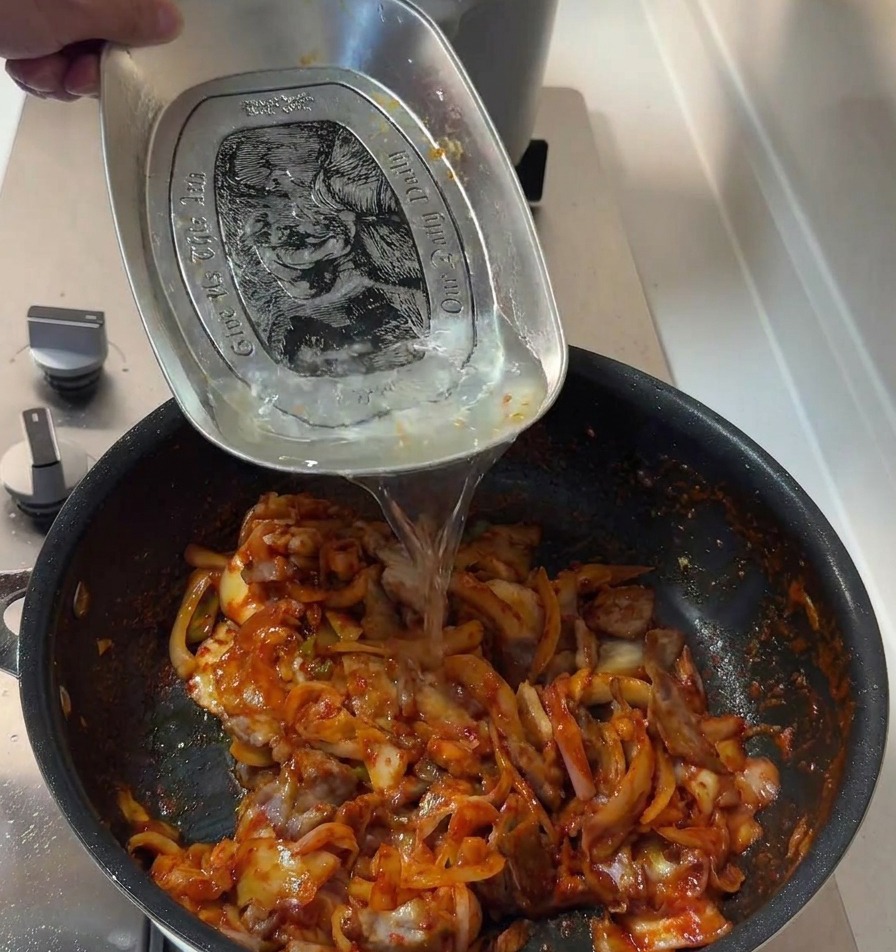 Etwas Wasser wird in die Pfanne mit dem scharfen Schweinefleisch und Kimchi gegossen, um die Sauce abzurunden.