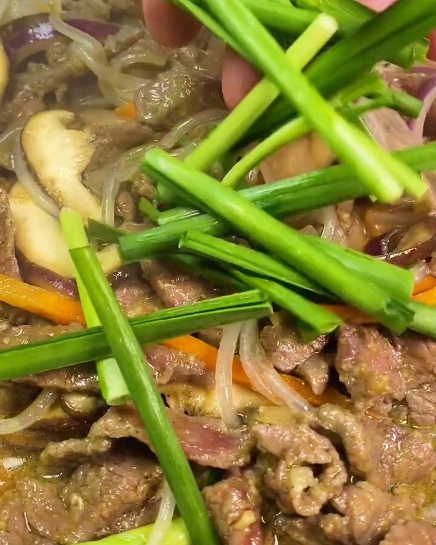 Frischer grüner Knoblauch-Schnittlauch wird zu dem fertigen Fleisch und den Glasnudeln in die heiße Pfanne gegeben.
