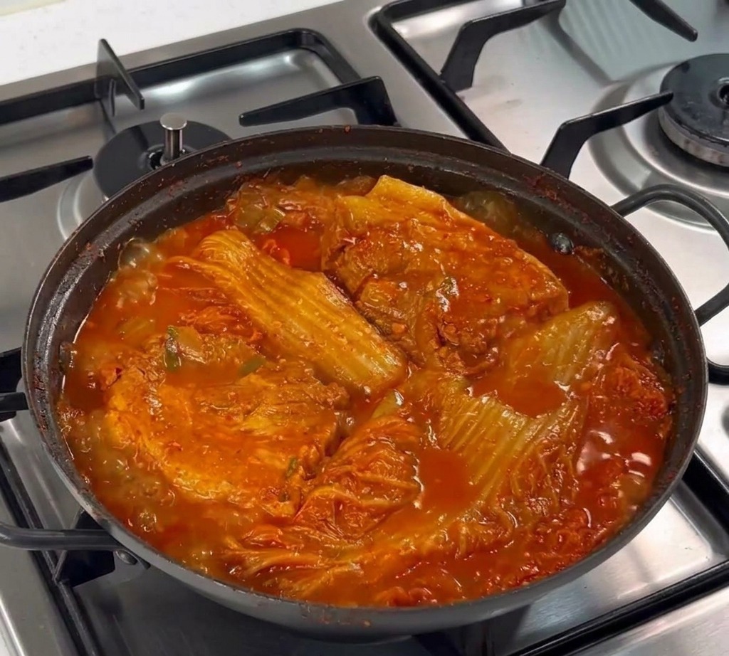 Ein Löffel gehackter Knoblauch wird auf den rohen Schweinebauch in der Pfanne gegeben.