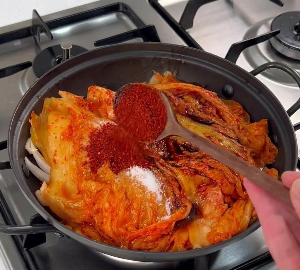 Rote koreanische Chiliflocken werden über die Zutaten im Topf gestreut.
