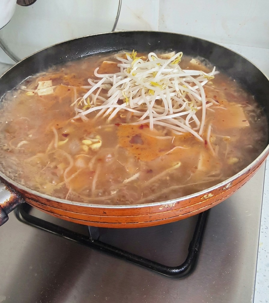 Ein ordentlicher Haufen frischer Sojasprossen wird auf die köchelnde Suppe gegeben.