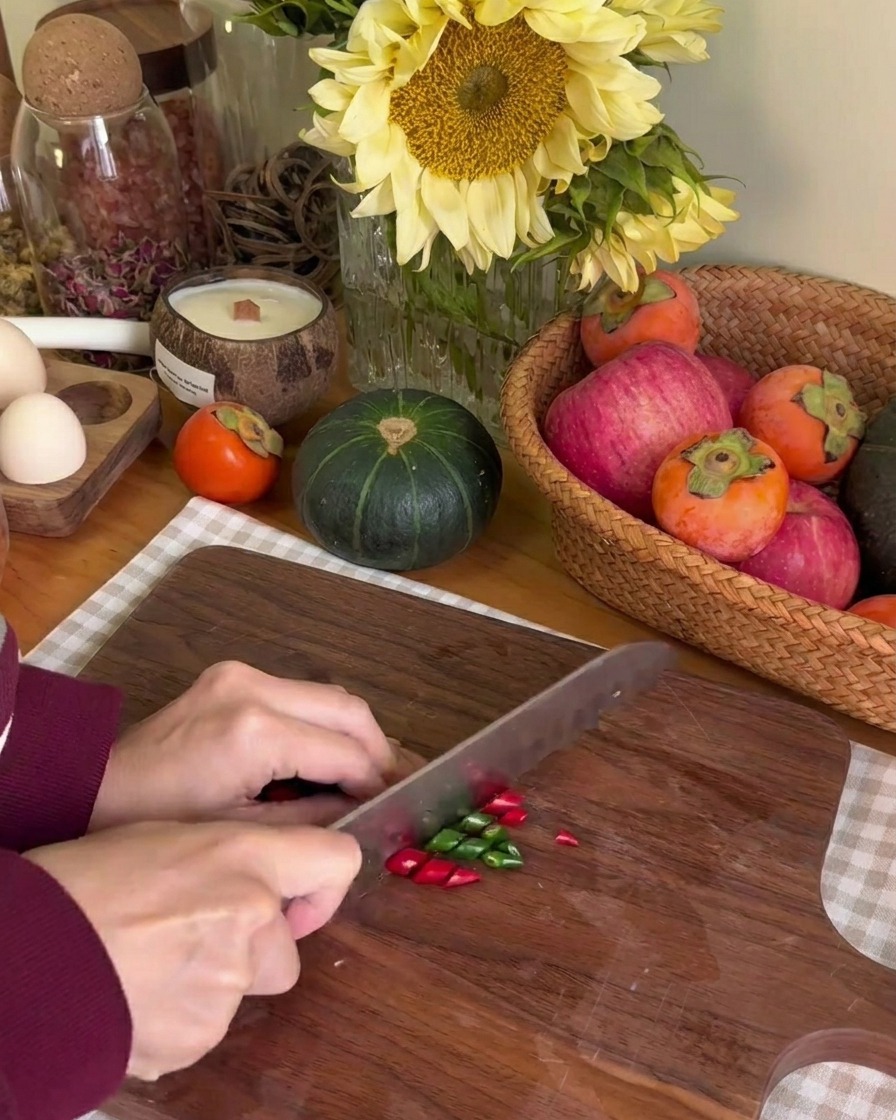 Fein geschnittene Ringe von roten und grünen Chilischoten auf einem Holzbrett